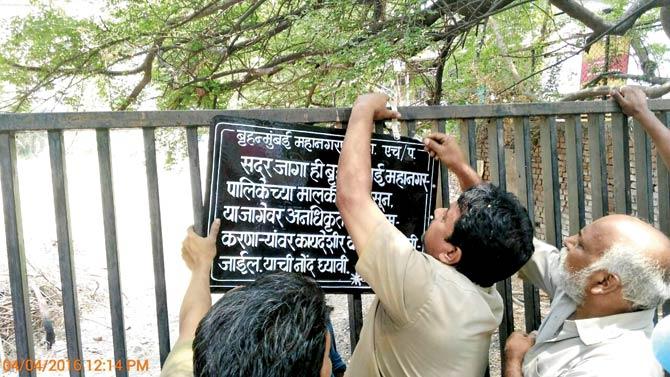 An official puts up a notice marking the plot as BMC property