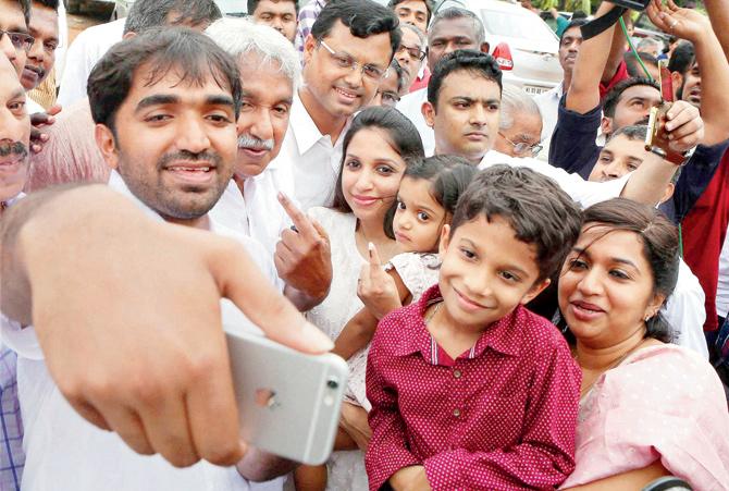 Kerala CM Oommen Chandy poses for a selfie with his family outside the polling station at Puthuppalli, Kerala. PICS/PTI