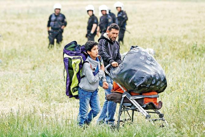A migrant family carries their belongings during the evacuation operation by police forces of a makeshift migrant camp at the Greek-Macedonian border near Idomeni yesterday. Pic/AFP