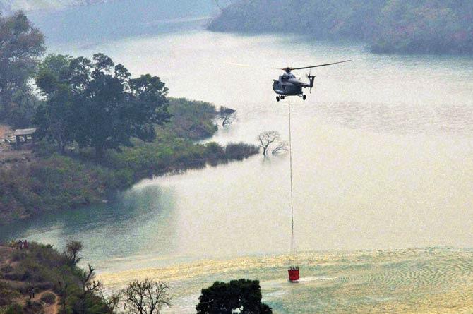 An IAF chopper collects water from Koteshwar dam during the rescue operation to control fire in Uttarakhand yesterday. Pic/PTI