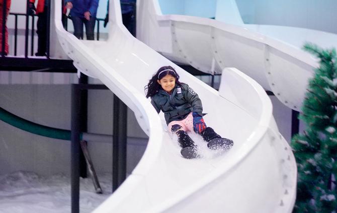 A little girl enjoys a snow slide ride