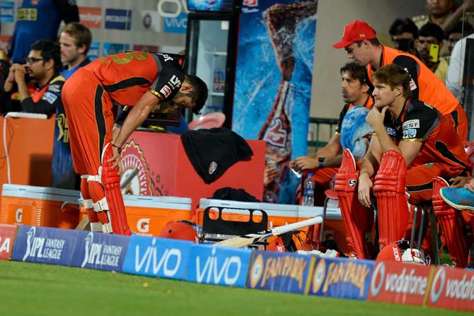 Royal Challengers Bangalore captain and batsman Virat Kohli bends down with disappointment in the players dug out after being bowled out during the final Twenty20 cricket match of the 2016 Indian Premier League (IPL) between Royal Challengers Bangalore and Sunrisers Hyderabad at The M. Chinnaswamy Stadium in Bangalore on Sunday night