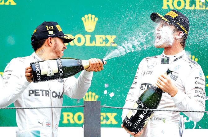 Mercedes driver Lewis Hamilton (left) sprays champagne over the face of teammate Nico Rosberg on Sunday. Pic/AP, PTI