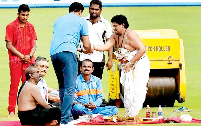 A priest gives prasad to Team India coach Anil Kumble after a 
