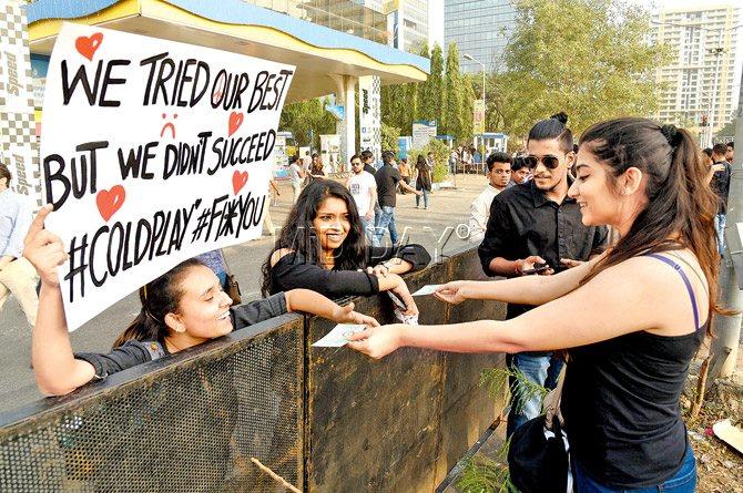 A young woman hands her passes to two others who did not manage to bag entry for Coldplay performance, and were protesting until they got lucky. Pic/Rane Ashish