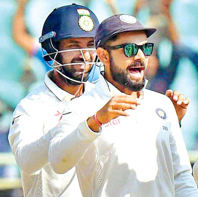 Virat Kohli (right) and Cheteshwar Pujara celebrate a wicket in Vizag yesterday