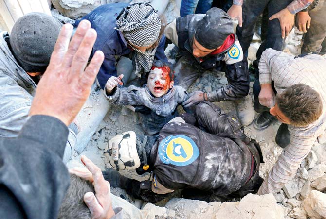 Syrian civil defence volunteers, known as the White Helmets, rescue a boy from the rubble following a reported barrel bomb attack on the Bab al-Nairab neighbourhood of Aleppo. Pic/AFP