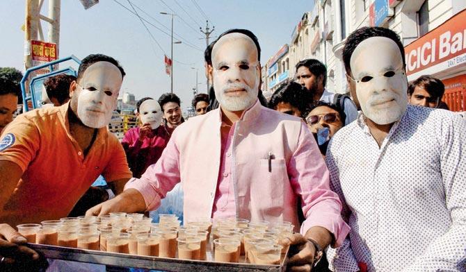 BJYM workers wearing masks of PM Narendra Modi serve tea to people lined up outside banks and ATMs to get their old currency exchanged in Bhopal. The government will introduce a system in which customers exchanging defunct currency notes will be marked with indelible ink. Pics/PTI