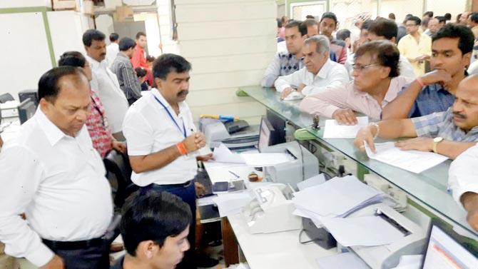 People queue up at the Ulhasnagar Municipal Corporation office to pay property tax as (left) civic commissioner Rajendra Nimbalkar and PRO and assistant municipal commissioner Yuvraj Badane look on. Pic/Navneet Barhate