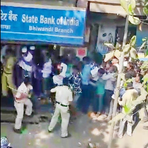 A grab from a video shot by a customer shows a policeman hitting people with his lathi outside the SBI at Bhiwandi