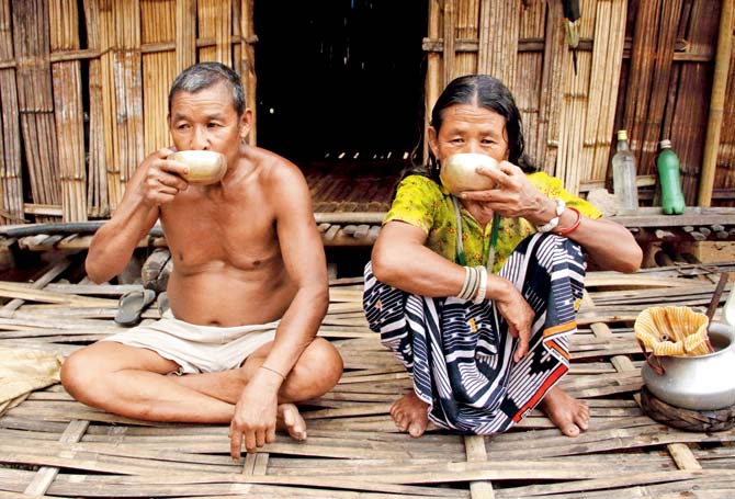 An elderly couple drinks the local liquor, Eu, from copper bowls