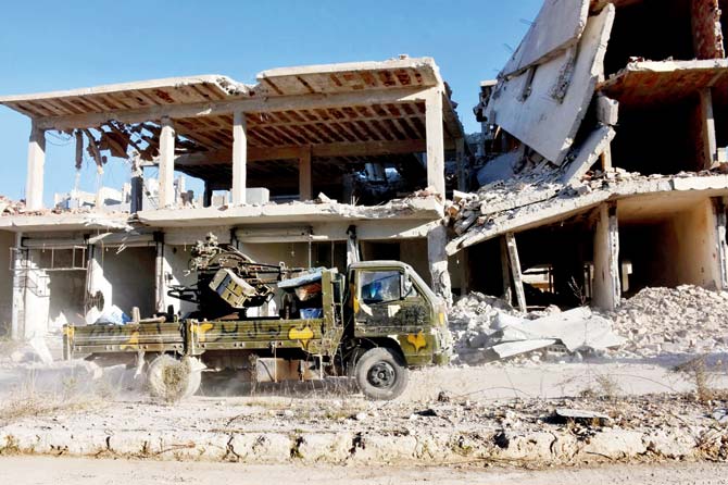 A vehicle of Syrian pro-government forces drives past damaged buildings in the Masaken Hanano district in eastern Aleppo, after they resized it from rebel fighters. Pic/AFP