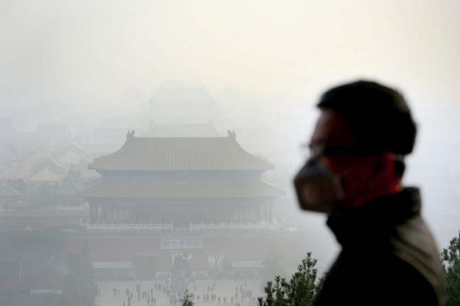 A tourist wearing a face mask visits a park near the Forbidden City during heavy smog in Beijing. Pic/AFP