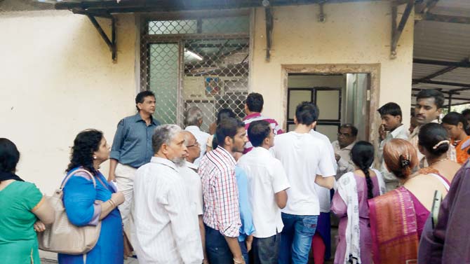 Patients stand in a queue to exchange their old currency at the counter opened by the postal department