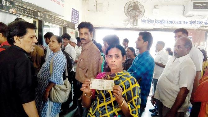 Woman shows her old Rs 500 note that she hopes to use to get a ticket