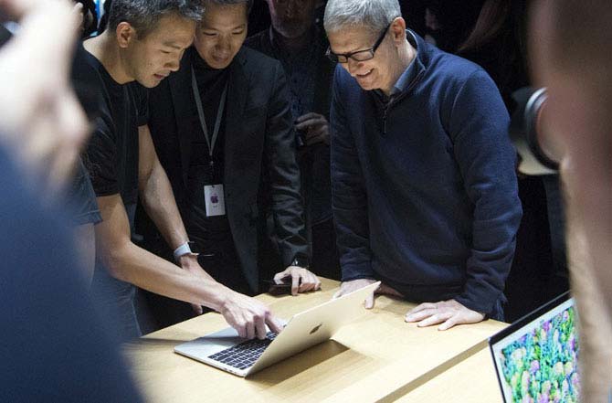 Apple CEO Tim Cook (R) previews a MacBook Pro during a product launch event at Apple headquarters in Cupertino, California on October 27, 2016. Photo: AFP