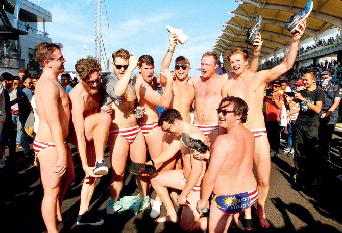 Australian men celebrate in Budgy Smuggler-brand swimsuits decorated with the Malaysian flag at the conclusion of the Malaysian Formula One Grand Prix in Sepang on Oct 2. Pic/AP,PTI 