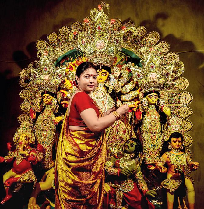 At the Banerjee bari, Meenakshi Banerjee puts a gold and pearl necklace on the idol before the Shashti evening puja 