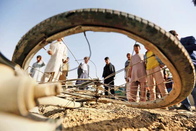 Afghan civilians look at a damaged bicycle after a bomb explosion targeted an army vehicle in Kabul. Pic/AP