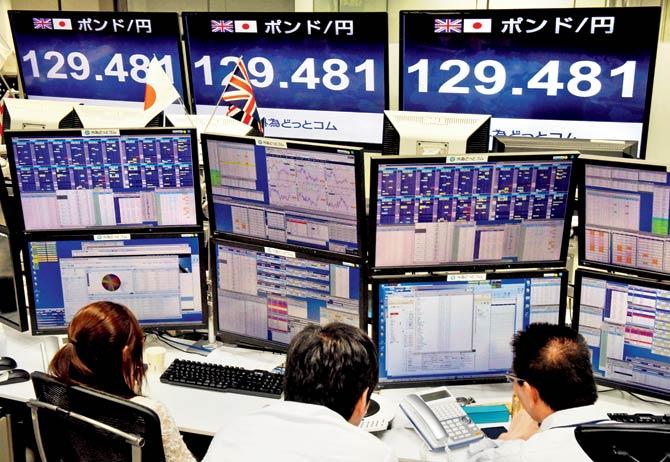 Operators in Japan watching as the value of the pound drops. Pic/AFP