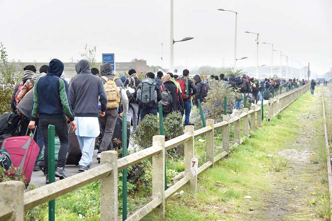 French riot police officers hold back migrants, as part of a major three-day operation planned to clear the “Jungle” migrant camp in Calais. Pics/AFP