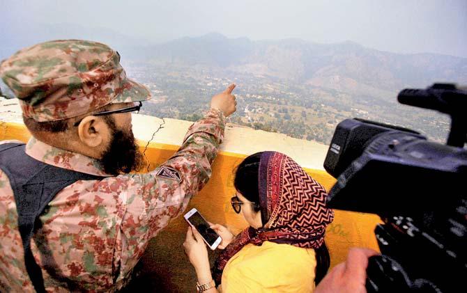 A Pakistan army officer points out the Indian forward area posts to journalists at Bagsar post on the LoC. Pic/AFP