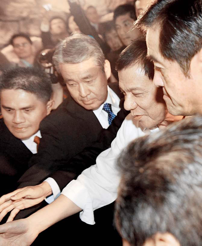 Philippines’ President Rodrigo Duterte (2nd R) shakes hands with supporters on his arrival in Tokyo on Tuesday. Pic/AFP
