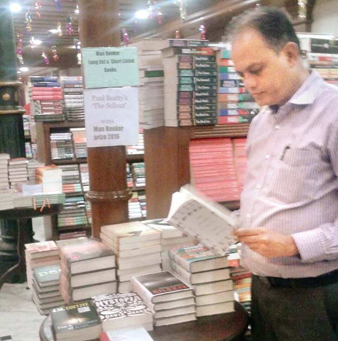 T Jagath, manager at KitabKhana holds the The Sellout in front of the corner for Man Booker shortlisted books at the store 