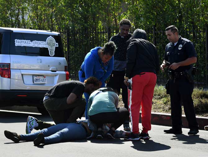 A woman faints after discovering her partner and father of her child was among the three people killed during a shooting after a dispute at a pop-up Jamaican restaurant in Los Angeles on October 15, 2016 Three people were killed and at least a dozen more injured, police said Saturday. One person has been arrested and police have launched a manhunt for another in connection with the deadly incident in West Adams, in the southwestern part of the metro area, said spokesman Lieutenant Chuck Springer.