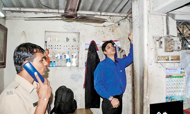 Owner Manoj Ochani points to the cracks in the wall at the police station