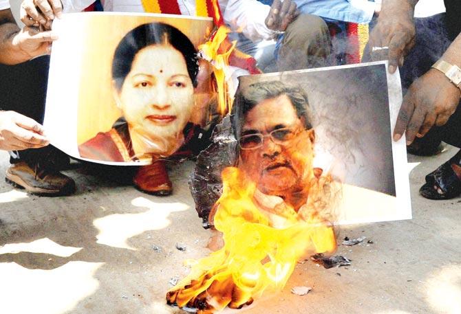 Activists burn posters of Tamil Nadu CM J Jayalalithaa and Karnataka CM Siddaramaiah. Pics/PTI