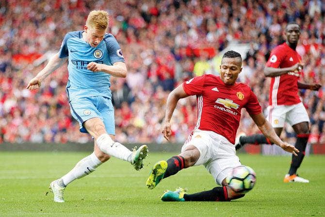 Kevin De Bruyne of Manchester City shoots past Manchester United’s Antonio Valencia during their English Premier League match at Old Trafford on Saturday. Pic/Getty Images 
