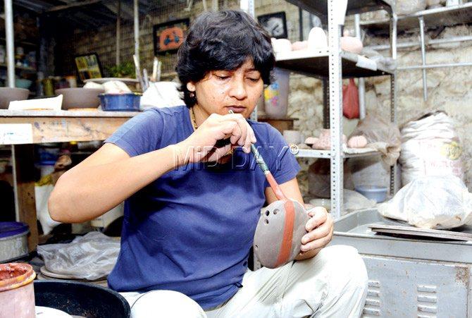Devyani Smith applies a coat of slip on a clay vase at her studio in Goregaon