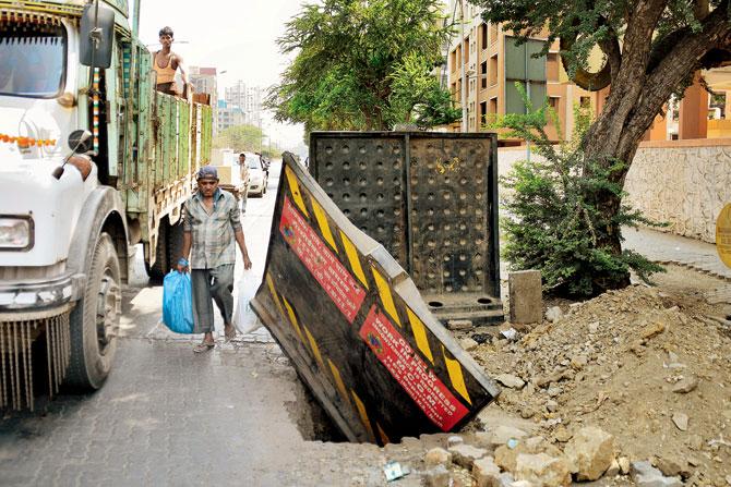 Traffic and pedestrians weave their way around a road fence that serves to warn against a deep crater at a dug up stretch at Ashok Nagar, Borivali (West). File Pic