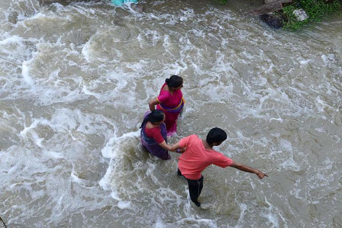 Women receive assistance as they make their way through floodwaters following heavy rain in Nijampet, a low lying area on the outskirts of Hyderabad. Pic/ AFP