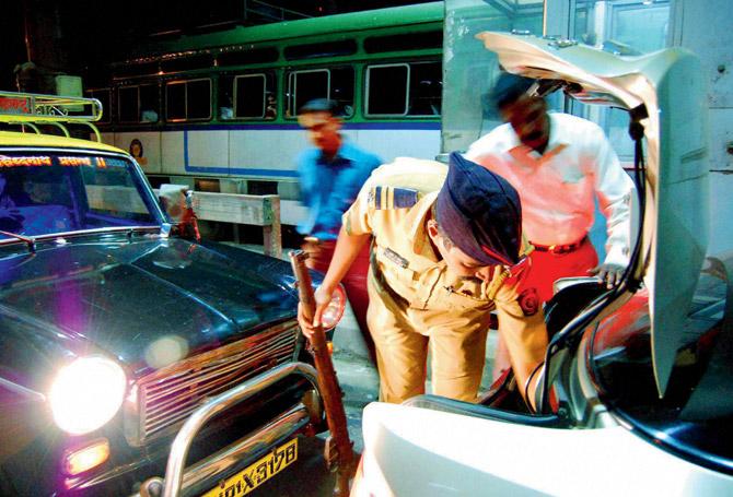 Policemen check vehicles at Vashi toll plaza in Navi Mumbai on Friday. Pic/PTI