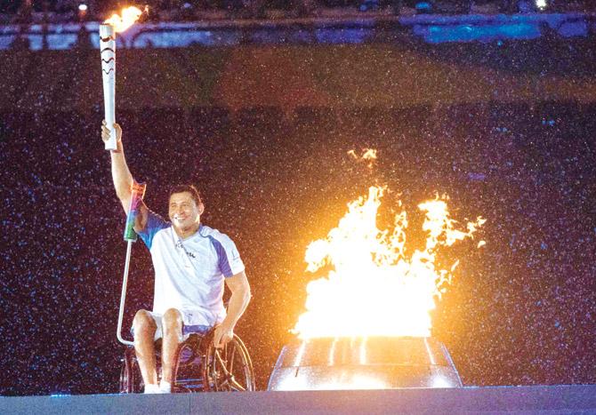 Brazilian swimmer Clodoaldo Silva holds up the torch after lighting the Paralympic cauldron