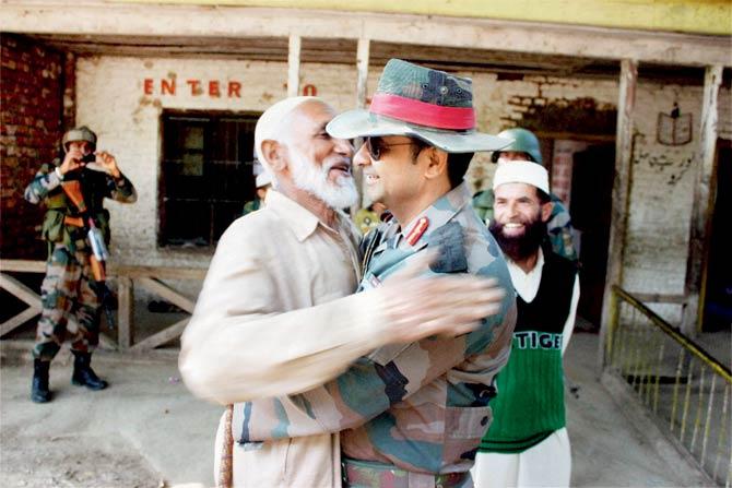 Col Dharmendra Yadav gives a ‘jadoo ki jhappi’ (magical hug) to a local Imam at Rainpora in Anantnag district. Pic/PTI
