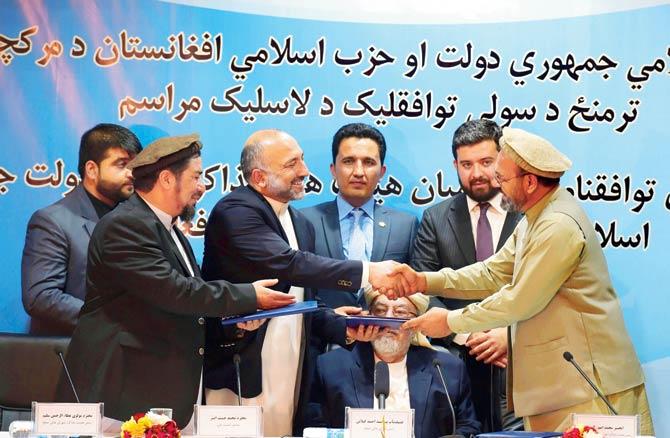 Afghan National Security Adviser, Hanif Atmar shakes hands with Amin Karim,(R), representative of Afghan warlord Gulbuddin Hekmatyar after signing a peace agreement in Kabul. Pic/AP