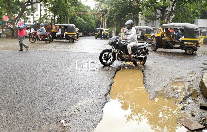 A motorist deftly manoeuvres his vehicle to avoid a pit at Mahavir junction in Kandivli West, as  another pothole on the same stretch turns into a culvert. Pics/Suresh Karkera