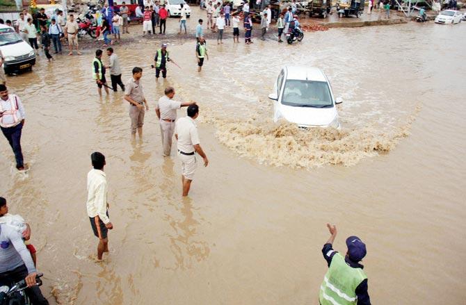 A car trudges through a waterlogged road in Gurgaon. Although monsoon this year was average, 37% districts still fall short of rain. Pic/PTI