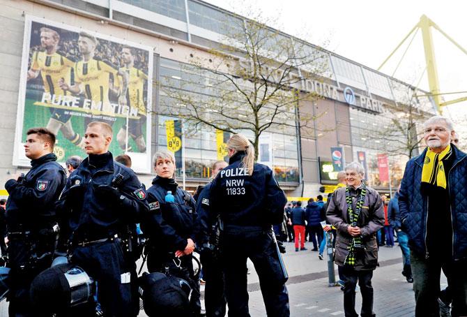 Police patrol outside the stadium after the Borussia Dortmund team bus was hit by an explosion and Marc Bartra (right) was injured. Pics/AFP