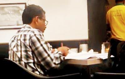 The teacher is seen checking papers at a restaurant in the video