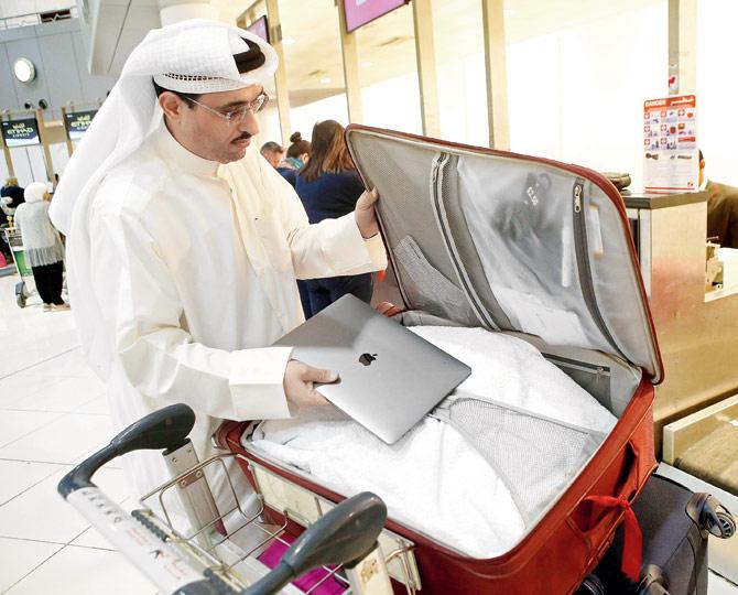 Social media activist Thamer al-Dakheel Bourashed puts his laptop in his suitcase at Kuwait airport before boarding a flight to the US, which in March banned fliers from the Middle East from carrying large electronics on board. Pic/AFP
