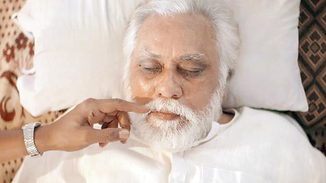 A still from Mukti Bhawan, where Adil Hussain’s character tries to confirm whether his 77-year-old father (Lalit Bahl) is breathing, only to have his hand swatted away