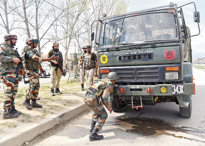 Army personnel look at a damaged vehicle after a convoy was attacked on the national highway in Srinagar on Saturday. Pic/AFP