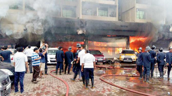 Fire officers outside the Maruti Suzuki showroom in Kharghar on Sunday