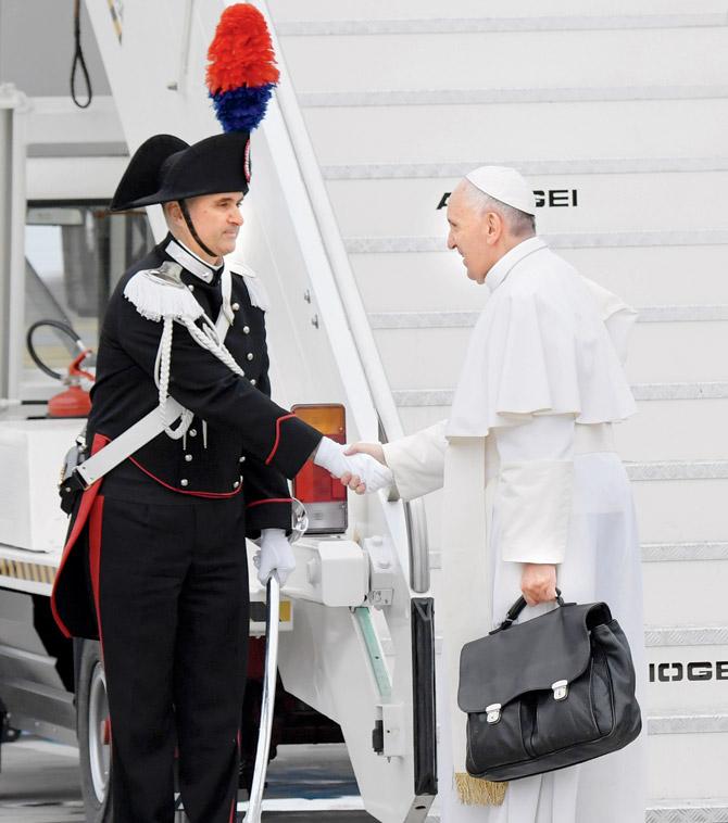 Pope Francis greets a guard before boarding a plane to Egypt