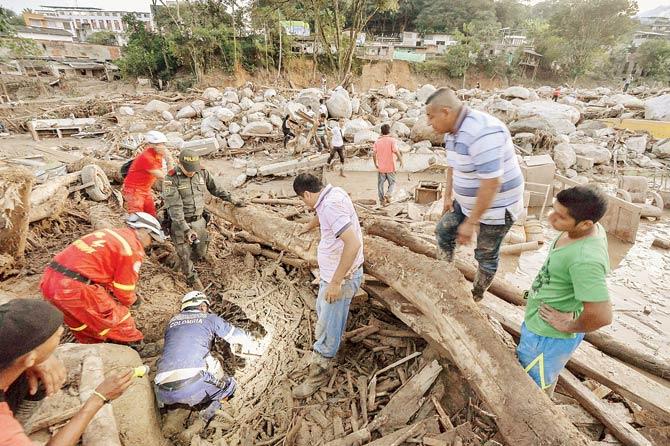 Rescuers seek people among the rubble left by mudslides. Pics/AFP