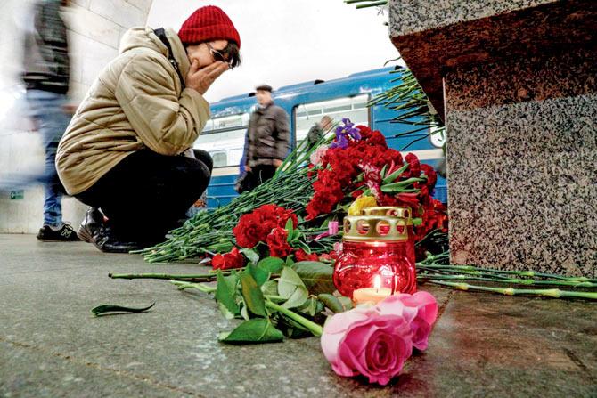 A woman reacts as she lays flowers at a memorial.